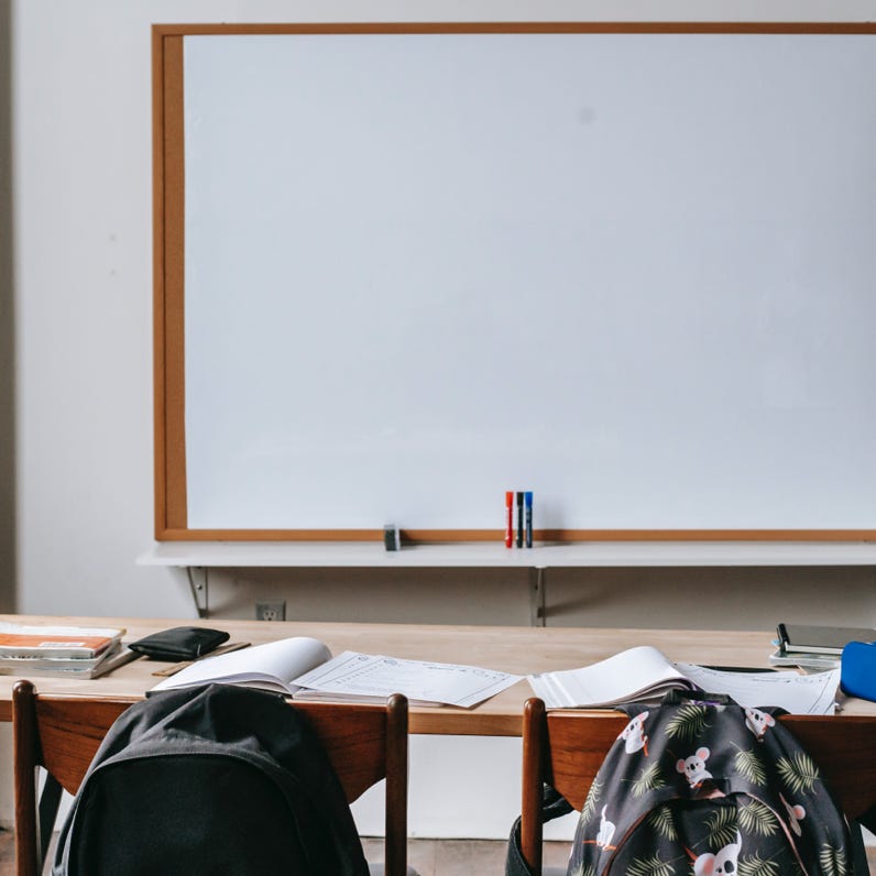 Classroom with whiteboard and desk with stationery